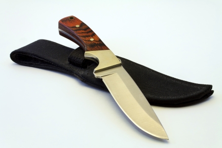 A steel knife with a wooden handle sitting on top of its sheath の写真素材