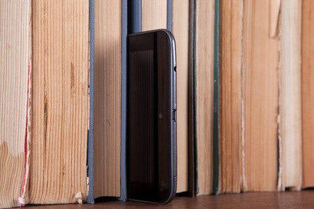 Tablet stands on a bookshelf with old booksの写真素材