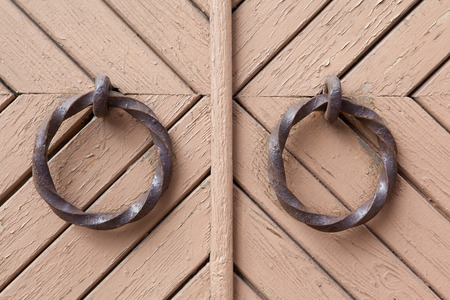 Dual old arched beige door with wrought handles rings.の写真素材