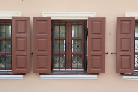 Brown windows frame with shutters in the wall arranged in a row