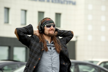 Young hipster fashion guy with beard. The man with the tablet and headphones on his head listening...