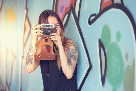 Girl teen with vintage camera against the wall and photographs.