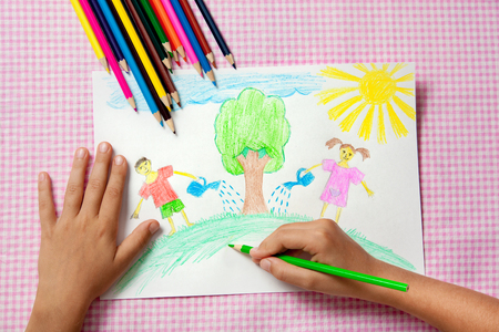 Child paints a picture of pencils about protecting nature. Children watering tree.の写真素材