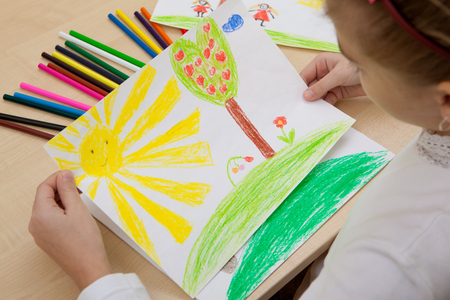 Girl watching a children's pencil drawing sun, summer, nature.の写真素材