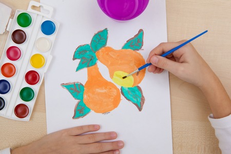 A child paints with watercolors on paper pears.の写真素材