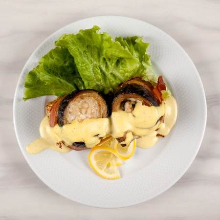 Eggplant and bacon rolls with cheese, lemon and green salad.の写真素材