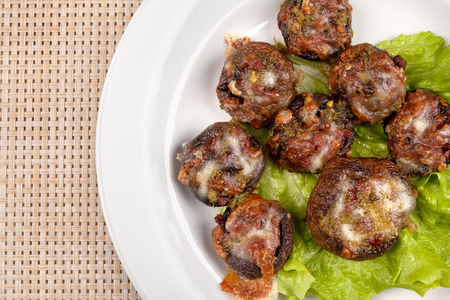 Baked champignon mushrooms stuffed with green salad on a white plate.の写真素材