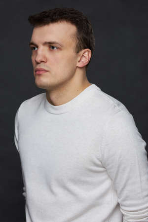 Portrait of a young man in the studio on a black background. Half a turn.