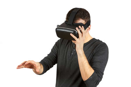 A young man with a virtual reality helmet on his head pulls his hand forward. The figure is isolated...