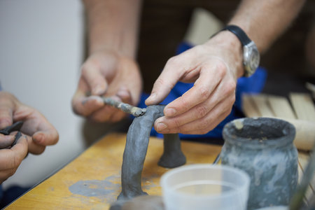 Pottery in the process of creation. Craftsmen sculpt a figure from the clay of a sculptors workshop.