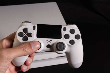 White game controller with gaming console at the background