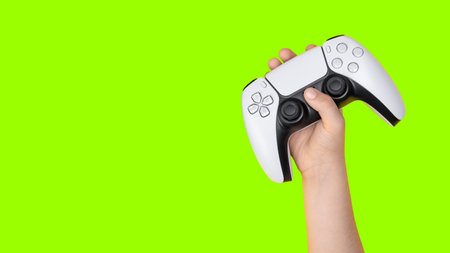 Kid holding game controller with green background for croppingの写真素材