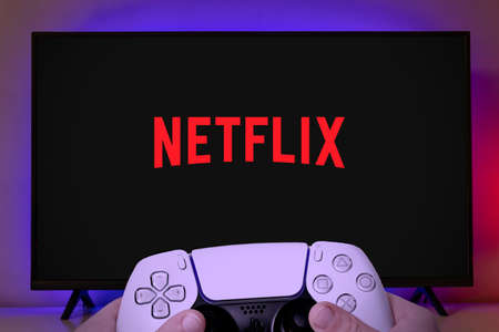Netflix logo at TV screen with man holding game controller. Netflix has announced that it will enter the online gaming market. 22 Jul, 2021, Sao Paulo, Brazil.のeditorial素材