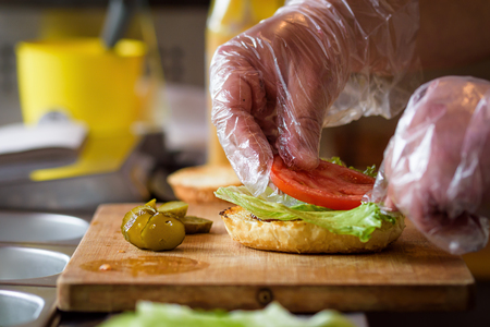Making Homemade Maxi Burger with grilled beef steak, lettuce, cheese, tomato, onion, barbecue sauce, honey mustard, picklesの写真素材