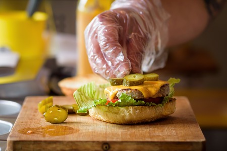 Making Homemade Maxi Burger with grilled beef steak, lettuce, cheese, tomato, onion, barbecue sauce, honey mustard, picklesの写真素材