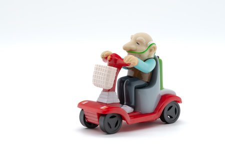Grandfather on motorized wheelchair, toys, white background, cropped imageの写真素材