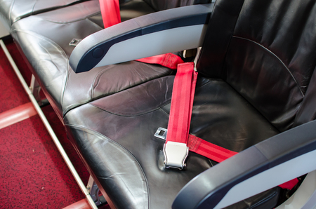 Seat belt on seat shot in airplane with Black seat and red carpet.の写真素材