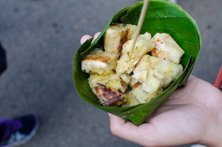 Hand of Asia Woman Carry Roasted banana in Banana Leaf ,Grilled banana or Roasted banana in Thai style Traditionalの写真素材