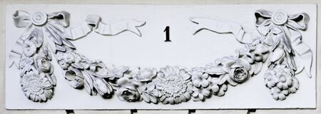 Number one on a facade with flower stone decoration in white