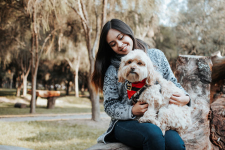 <p>Happy girl with her dog in the park. Dog on the legs of its owner in the park.</p>の写真素材
