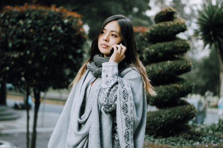 <p>Girl talking on the phone. Girl calling on the phone in the city. Background garden.</p>の写真素材