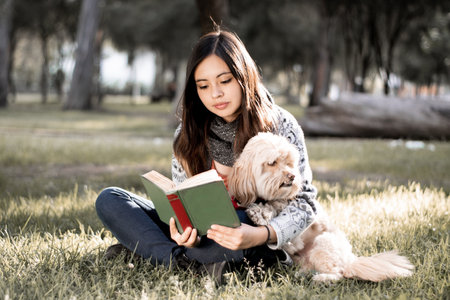 <p>Girl reading a book with her dog in the park. Girl sitting reading a book with her dog in the park.</p>の写真素材