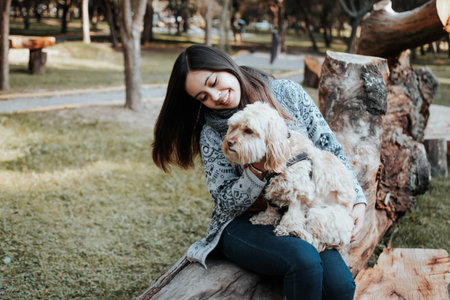 <p>Girl watching her dog in the park. The smiling girl hugs her dog.</p>の写真素材
