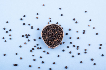 A wooden bowl filled with black pepper in a minimalist style. top view. Scattered black pepper.の写真素材