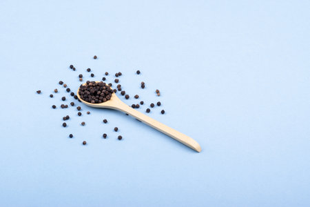 Wooden spoon with black pepper in a minimalist style. top view. Scattered black pepperの写真素材