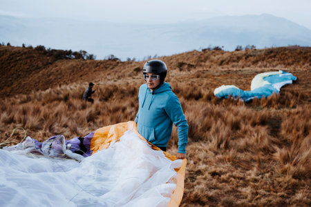 Man spreads wing to paraglide. A concentrated man prepares to jump.の写真素材