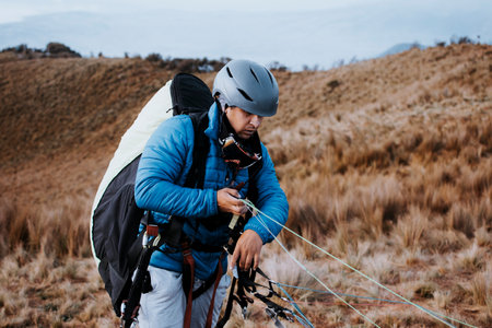 Man on the mountain prepares his paragliding flight. Concentrated man to start his paragliding flightの写真素材