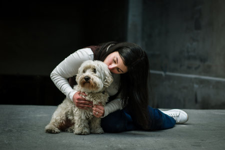 Girl kissing her dog in the city. Girl in love with her pet. Woman with her dog sitting on the...