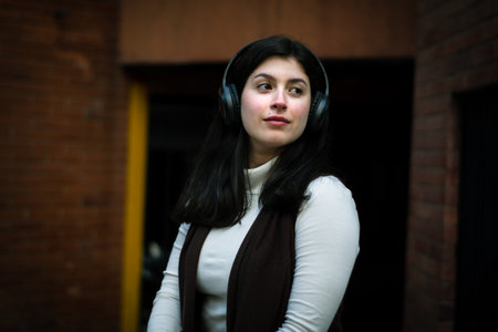 Thoughtful woman listening to music in the city. White woman with headphones listening to music. relaxed womanの写真素材