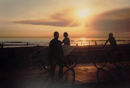 Cyclist and surfer on the Venice Beach backlit ride