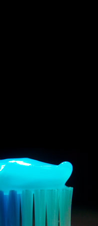 toothpaste brush in blue with black background in vertical with area for textの写真素材