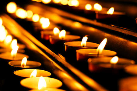 lit candles in row, detail of church petitions area, light up the dark