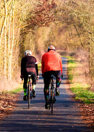old people practicing cycling in autumn on bike laneの写真素材