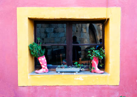 Window with recycled objects to decorate recycled rain boots as a pot for plants and rain gutter as...