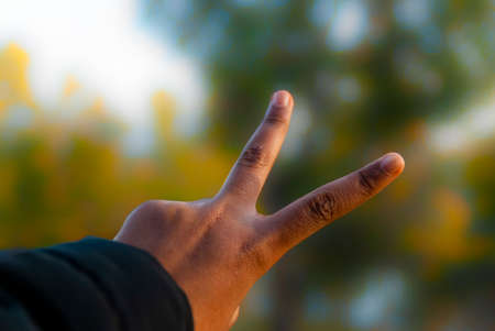 Sign of the victory with the fingers of the hand with unfocused background and copy spaceの写真素材