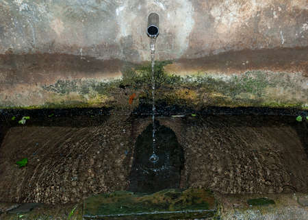 Stone fountain with flowing water with moss and smooth stoneの写真素材