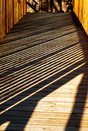 Shadows on wooden walkway with wooden railing forming vertical diagonal boxesの写真素材