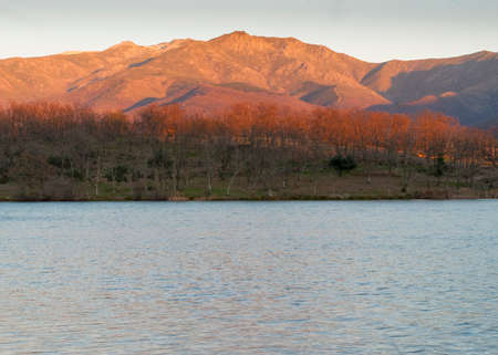 Mountain with orange light at sunset by the water lake in autumn