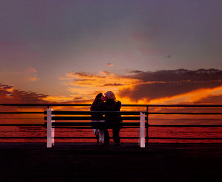 Silhouette of couple kissing at sunset on a bench on the Santa Monica Pier for Valentine's Dayの写真素材