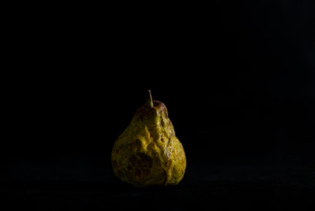 Ripe pear on dark black background horizontal about to spoilの写真素材