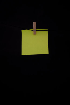 Post it yellow fluorescent with wooden clip with black background copy space annotation remember for textの写真素材
