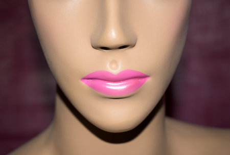 half face of woman mannequin with nose, mouth and lips painted pink with magenta horizontal backgroundの写真素材