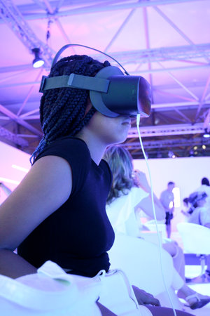 Girl in profile with braids wearing VR virtual reality glasses with light background in verticalの写真素材