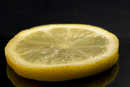 Macro detail of fresh yellow lemon slice split with black background horizontalの写真素材