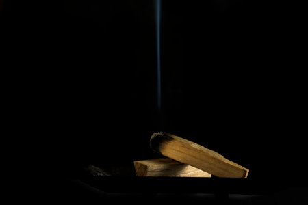 Bursera graveolens Palo Santo a burning sacred wood with smoke on a black background intense aroma...
