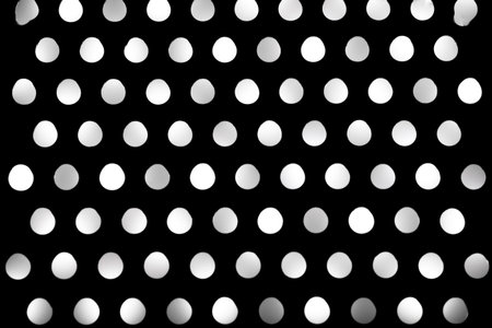 Abstract macro shot of a metal grater backlit by an LED light source. The holes create a bright pattern of glowing light and shadow, suitable for use as a technological or industrial stock background.の写真素材